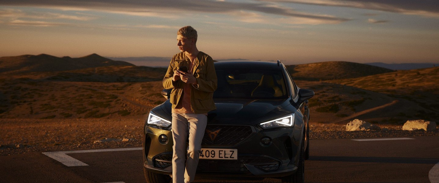 man-in-front-of-cupra-formentor-dark-camouflage-with-mobile-in-the-dessert