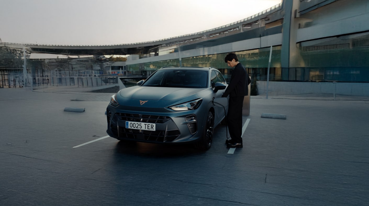 3/4 side view of a CUPRA Terramar plug-in hybrid plugged into an electric charger.