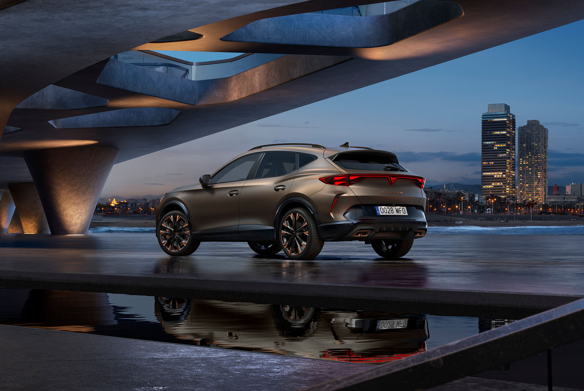 Rear three-quarter perspective of the new CUPRA Formentor hybrid car parked by waterfront and city skyline. The vehicle is angled to showcase its rear design, lights and sporty dual exhausts.