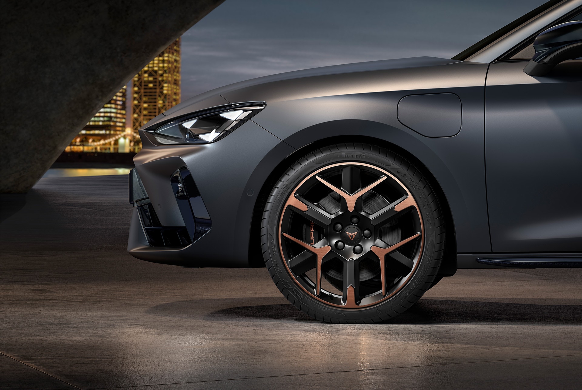 front side view of left forged alloy wheel in copper and black for the new Cupra Leon 2025, tyres, signature headlights and matt grey body.